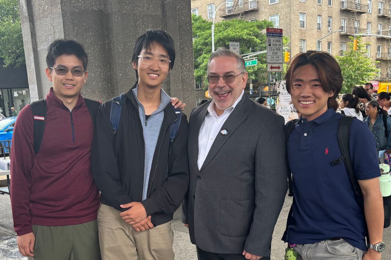 Three Novus students with a community partner at a neighborhood event